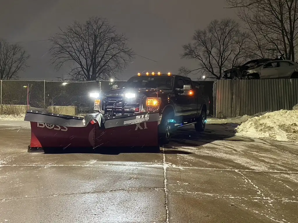Truck plowing heavy snowfall at night in a commercial lot