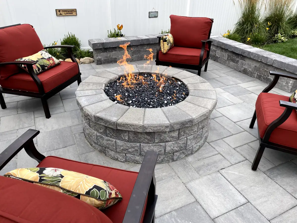 Built-in gas fire pit with fire glass surrounded by cushioned seating chairs