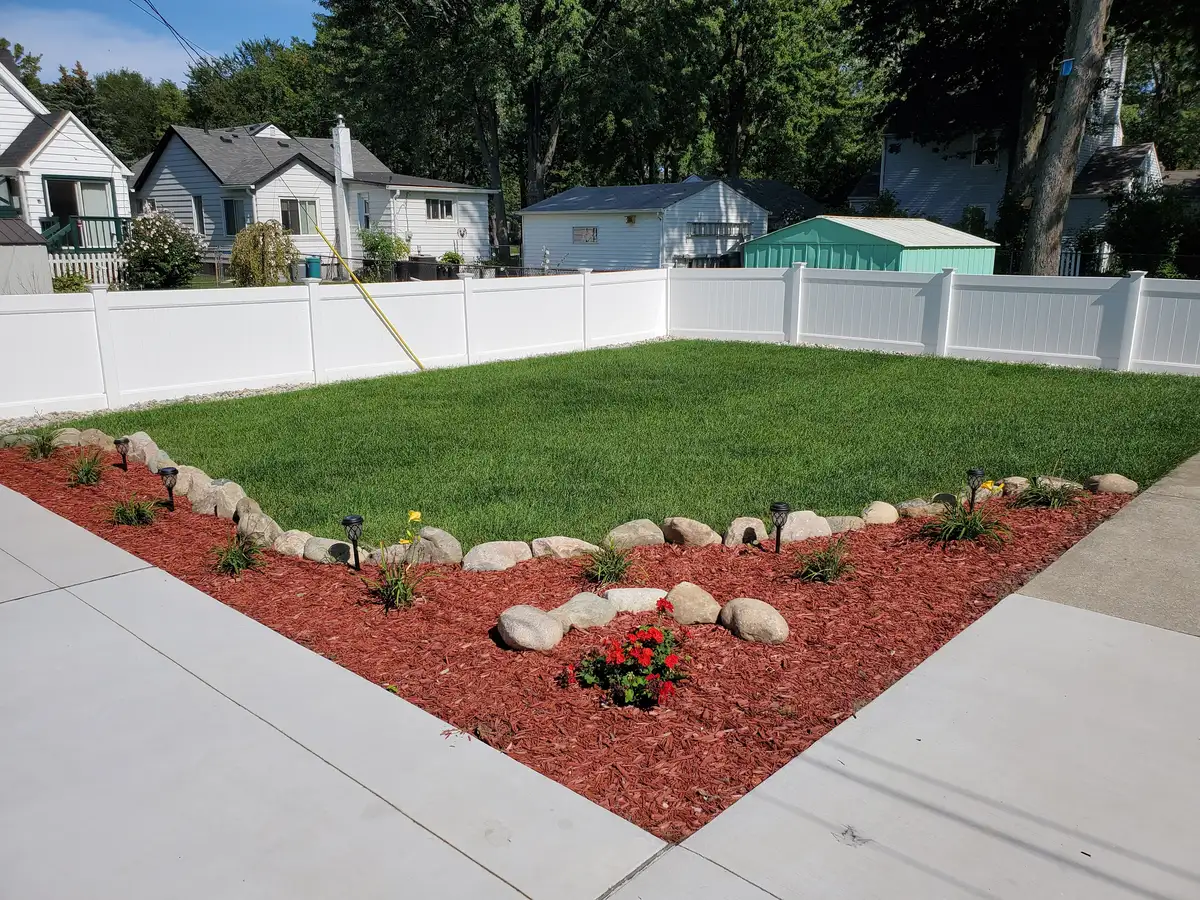 Corner yard with fresh sod, red mulch beds, boulder border, and solar path lights