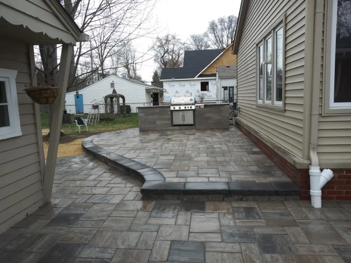 Custom outdoor kitchen with built-in grill island on multi-level paver patio by The Guy Outdoor Services