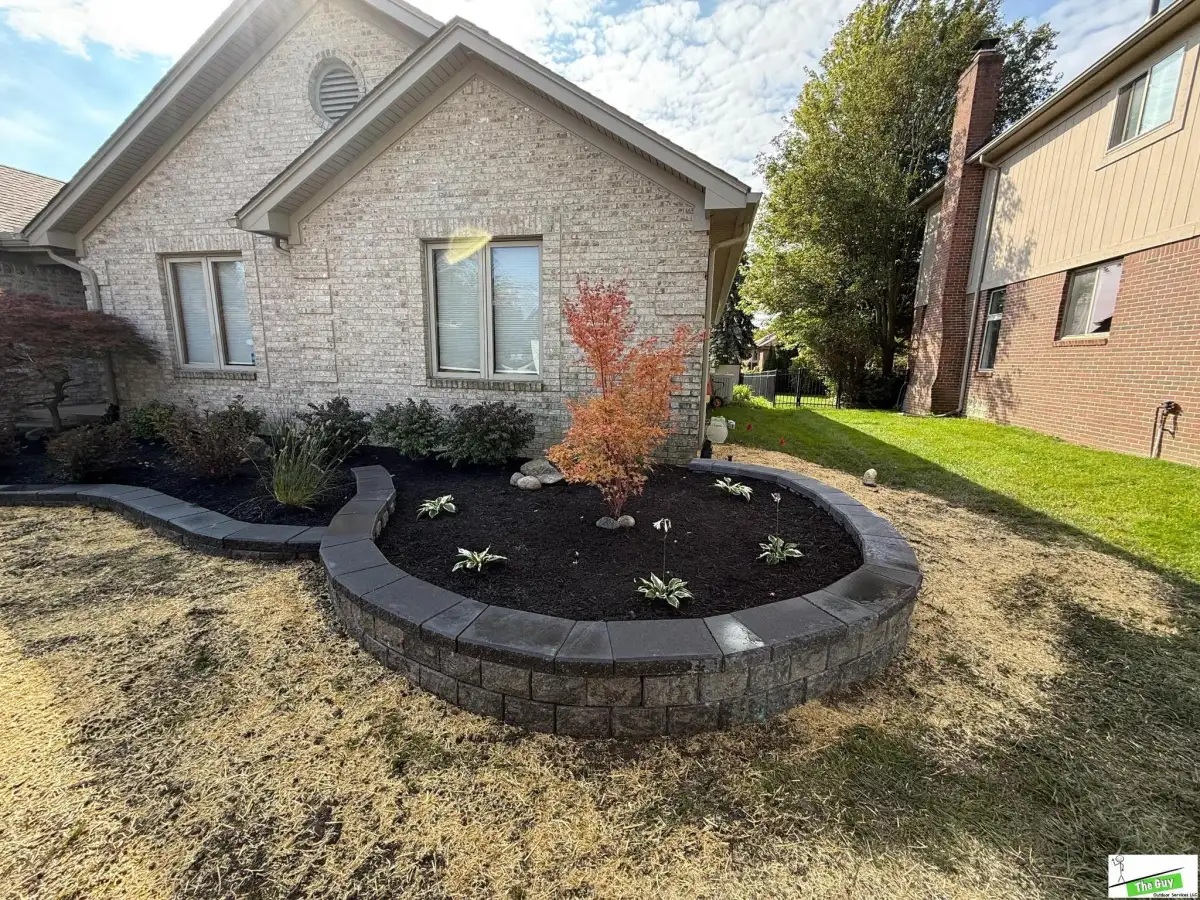Curved segmental block retaining wall with Japanese maple and landscape plantings by The Guy Outdoor Services