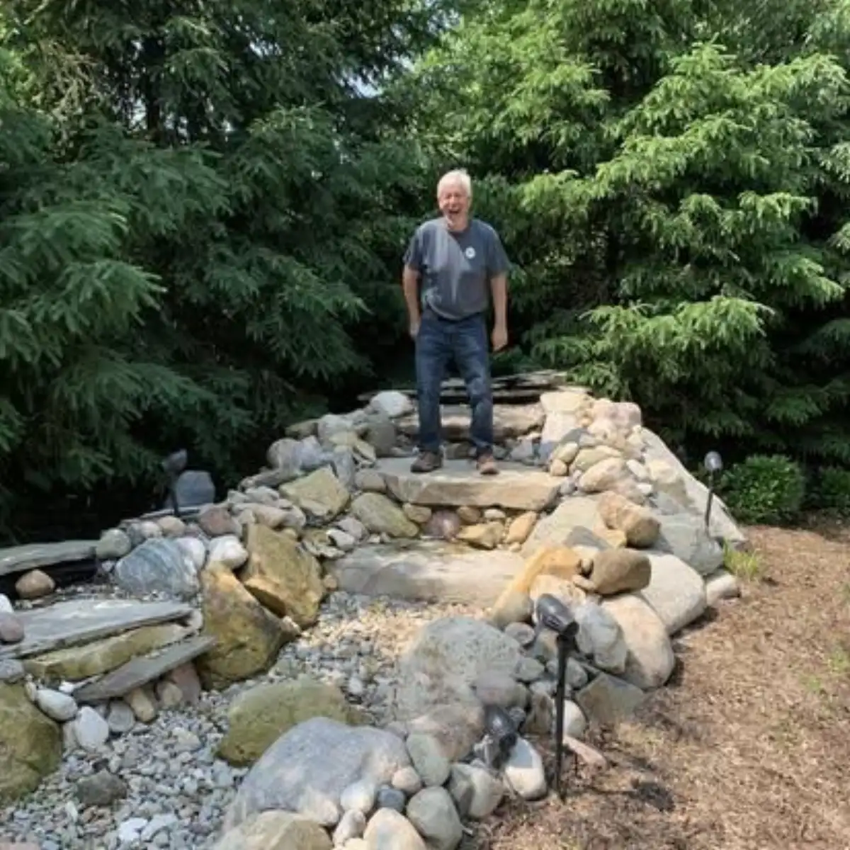 Owner of The Guy Outdoor Services showcasing a custom water feature build