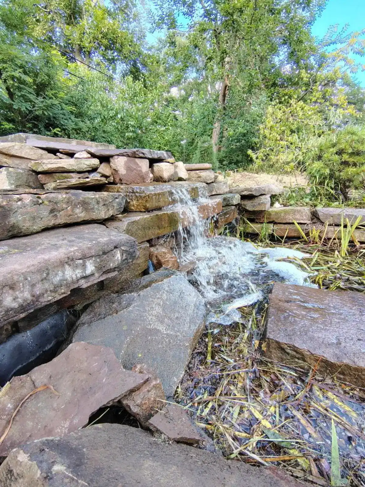 Signature vintage truck waterfall feature with cascading stone tiers by The Guy Outdoor Services
