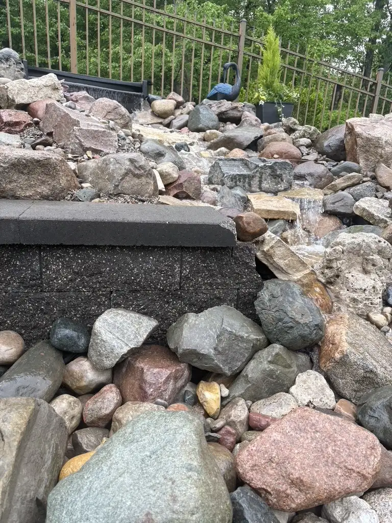 Pondless water feature with a stone spillway and river rock basin