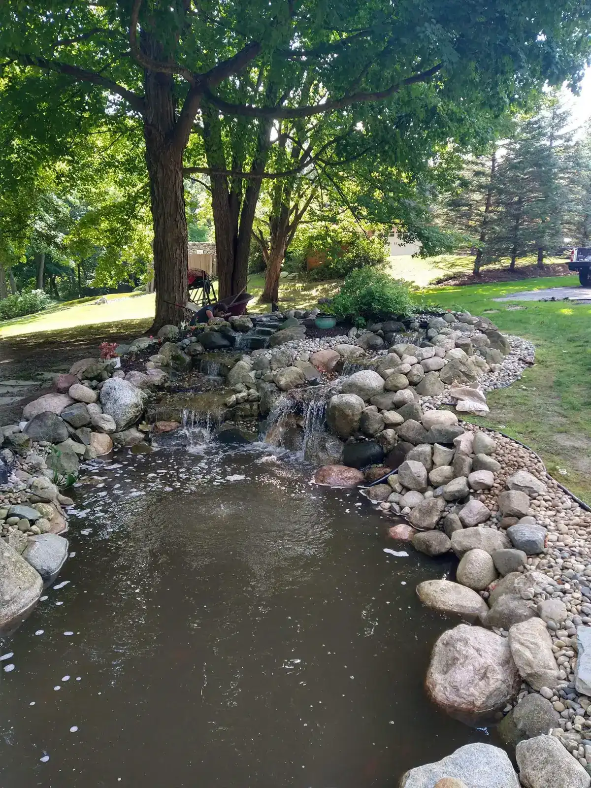 Natural stone waterfall and pond under mature shade trees