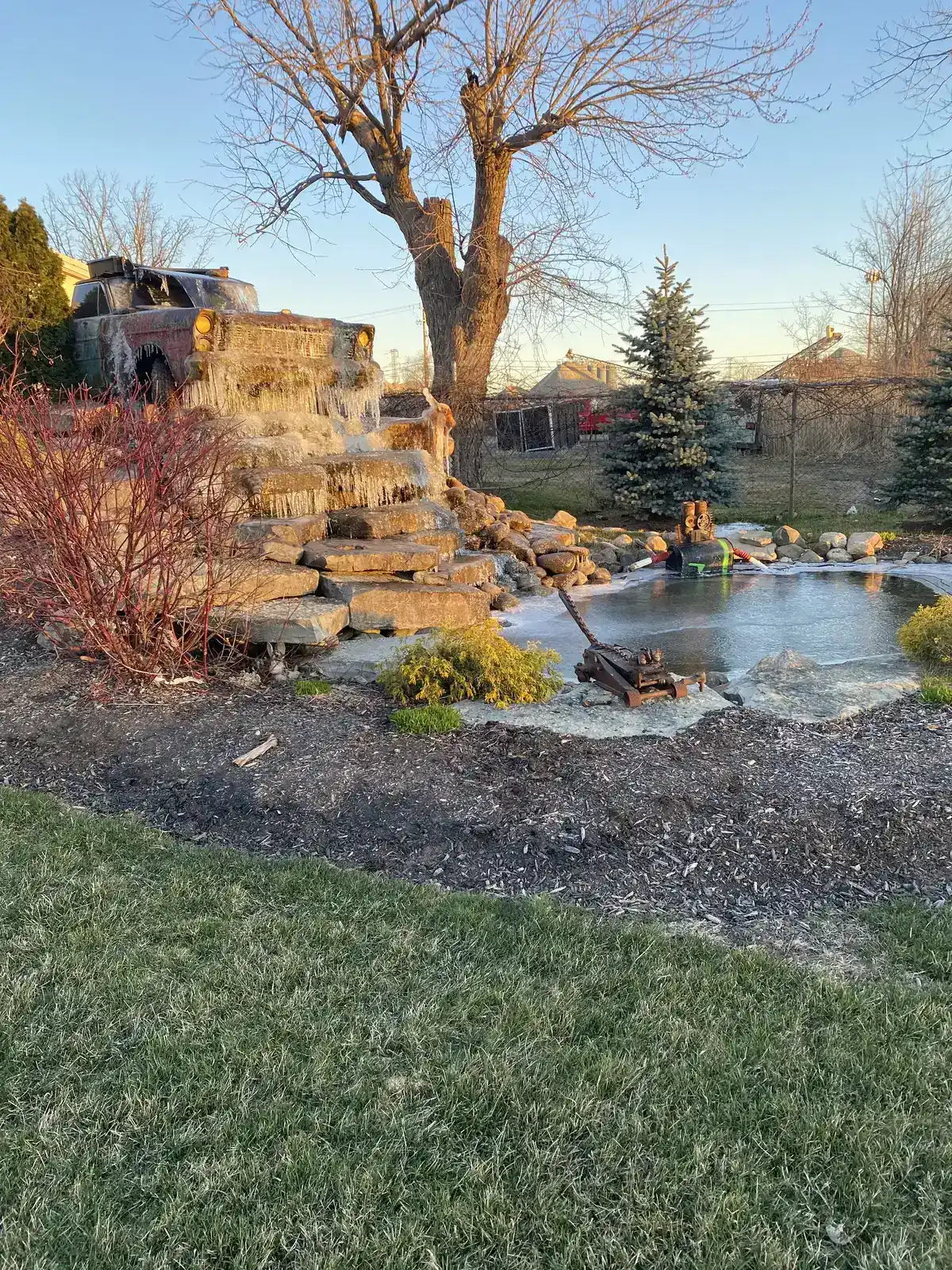 Decorative front yard garden pond with colorful flower border and stepping stones